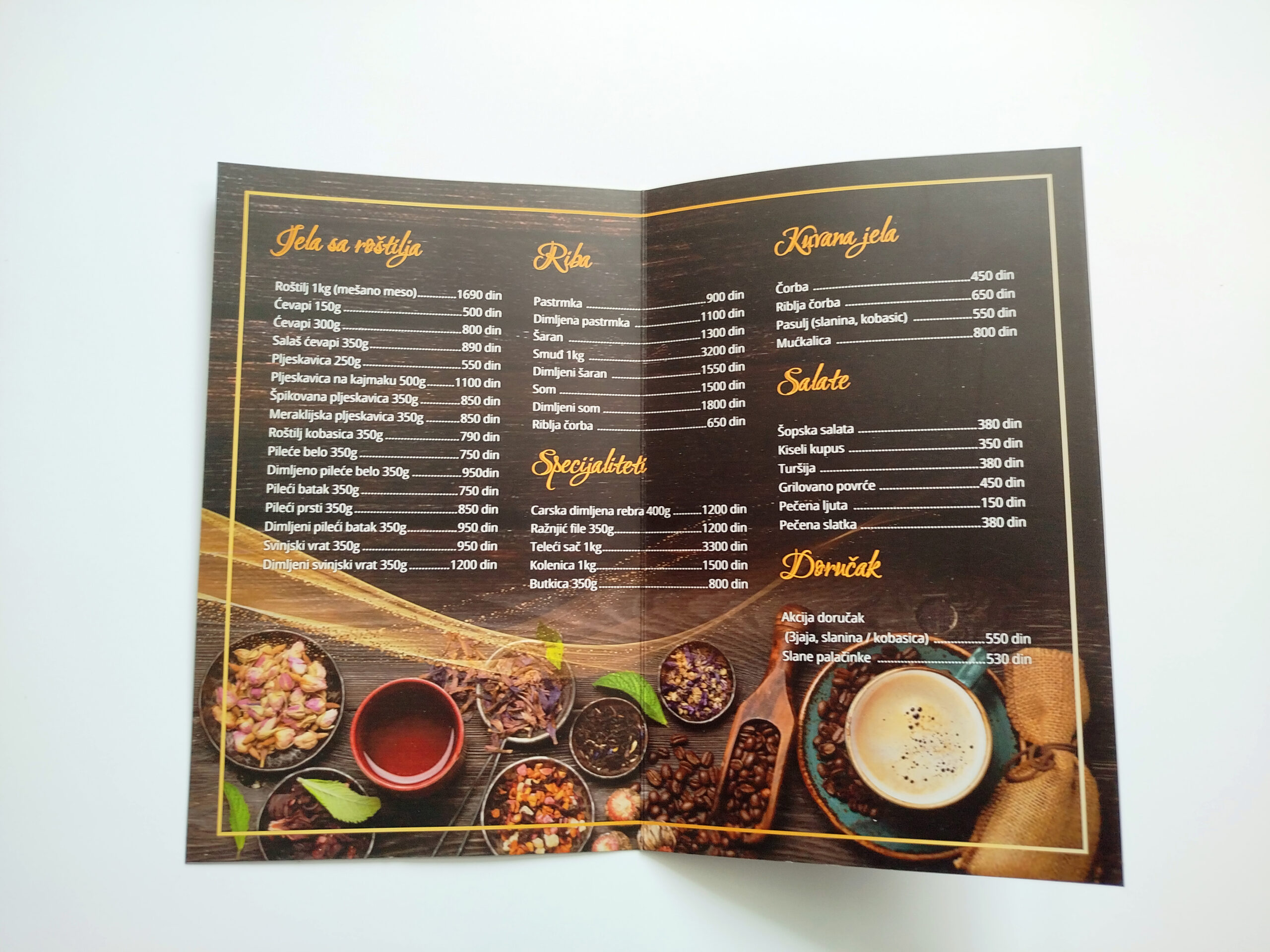 Naslovna strana restoranskog jelovnika sa elegantnim crnim i zlatnim dizajnom i jasno istaknutim vizuelnim identitetom. Fotografija prikazuje primer profesionalne štampe jelovnika za restorane, kafiće i ugostiteljske objekte.